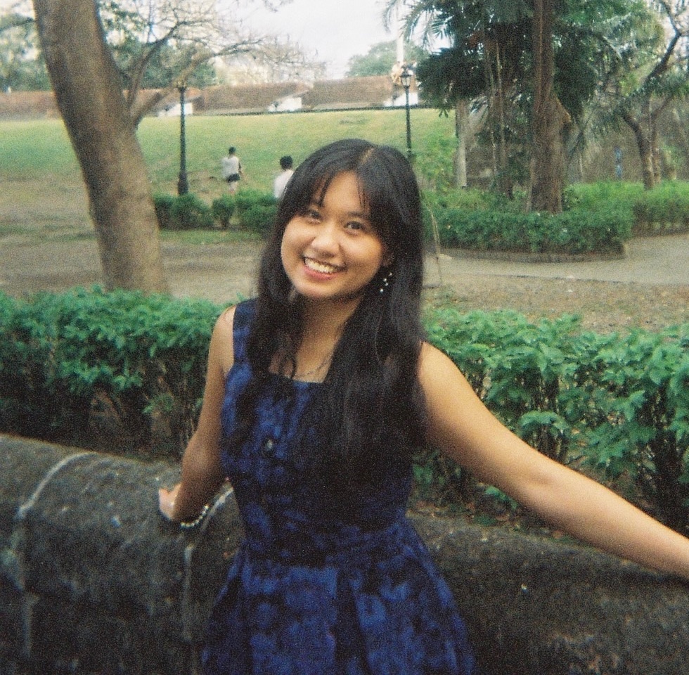 Elle Guison smiling in a blue dress in a park, shot on film